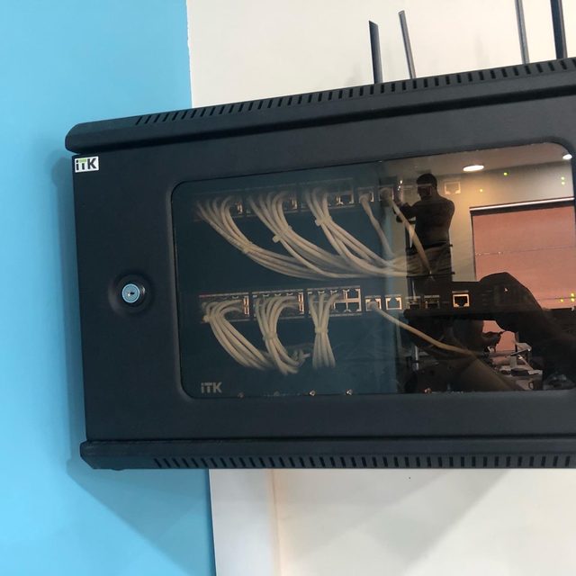 Glass-front wall-mounted network cabinet with organized patch cables